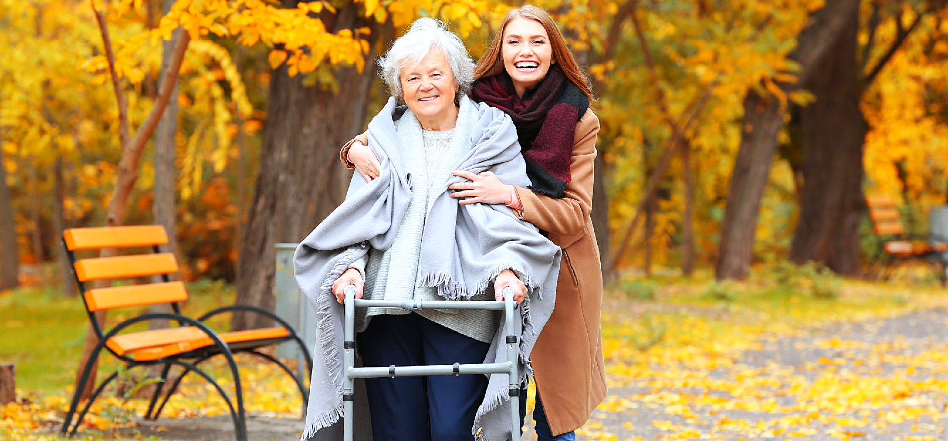 caregiver assisting senior woman to stand while smiling